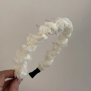 Détail du serre-tête en tulle plissé crème avec perles et dents antidérapantes