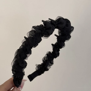 Détail d'un serre-tête en résille plissée noire avec perles et dents de peigne antidérapantes