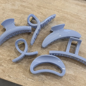 Flat lay of light blue resin hair claw clips set in various geometric shapes on a stone surface