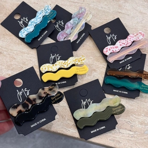 Elegant wavy acetate hair clips in assorted patterns and colors on black display cards