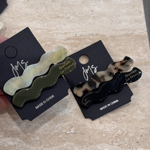 Detailed view of wavy acetate hair clips in marble and tortoiseshell patterns on card