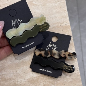 Detailed close-up of marble pattern acetate wave hair clips on a branded display card