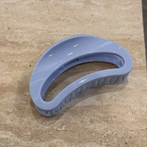 Detail view of the light blue crescent hair claw clip showing textured grip and glossy finish