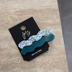 Detail of marble blue and teal wavy acetate hair clips on a black display card