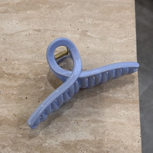 Close-up of light blue hair claw clip with glossy finish and gold metal spring details