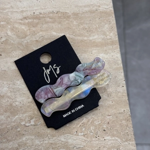 Macro shot of marble-patterned and iridescent wave hair clips on black display card