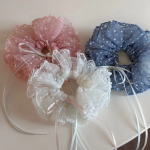 Détail de chouchous en dentelle à pois avec de longs rubans en rose, blanc et bleu ciel