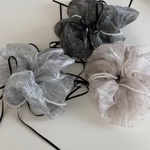 Close-up of glitter pleated hair scrunchies with white pearls and black ribbons