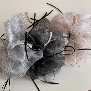 Detail view of shimmering fabric hair scrunchies with faux pearls and black ribbon bows