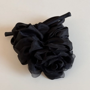 Détail d'un chouchou rose en organza noir avec pétales multicouches et rubans élégants