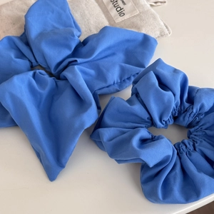 Klein blue scrunchie set featuring a large bow and classic pleated hair tie on fabric