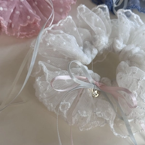 Détail d'un chouchou en dentelle à pois blancs avec nœuds satinés et cœur doré