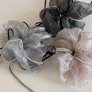 Detailed close-up of glossy scrunchies with white pearl beads and black ribbons