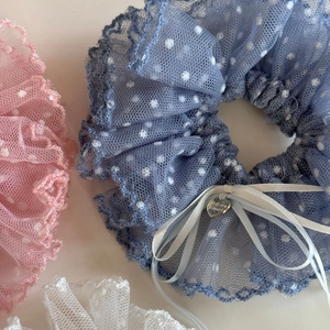 Gros plan détaillé de chouchous en dentelle à pois avec pendentif cœur en rose bleu et blanc