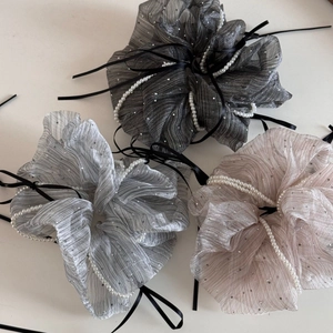 Close-up of three organza scrunchies with white pearls and black satin ribbons