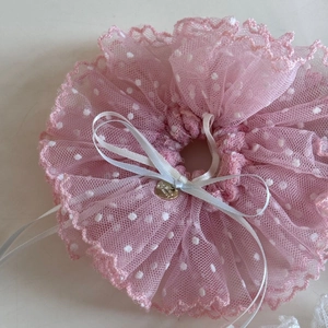 Détail macro du chouchou en dentelle rose avec ruban blanc et pendentif en forme de cœur