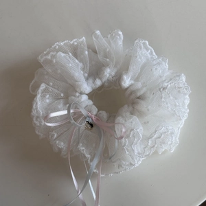 Gros plan sur chouchou en dentelle blanche à pois, rubans roses et pendentif de coeur
