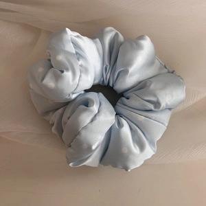 Detail view of a light blue polka dot satin scrunchie with soft pleats on white gauze