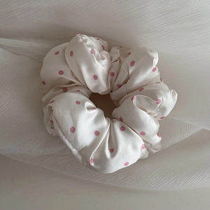 Detailed view of beige satin scrunchie with pink polka dots and soft smooth texture