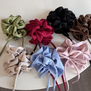 Chouchous en satin avec rubans en sept couleurs posés sur une surface blanche