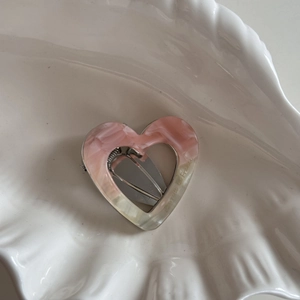Détail d'une barrette à cheveux en forme de cœur avec texture marbrée rose et blanc