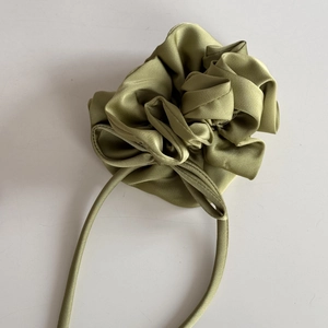 Vue détaillée du chouchou floral en satin vert olive avec de longs rubans décoratifs