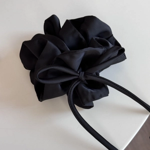 Détail d'un chouchou en satin noir avec un long ruban montrant sa texture soyeuse