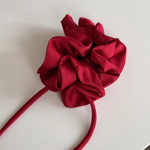 Détail d'un élastique à cheveux en satin rouge avec des pétales multicouches élégants