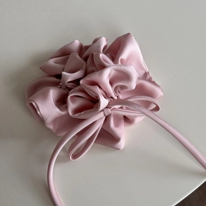 Vue détaillée d'un chouchou en satin rose avec rubans et texture de tissu brillant