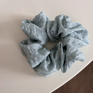 Vue détaillée d'un chouchou bleu clair à pois blancs avec une texture en tissu doux