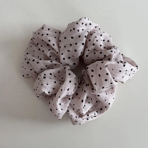 Détail du tissu en mousseline rose clair à pois noirs avec des plis doux et soyeux