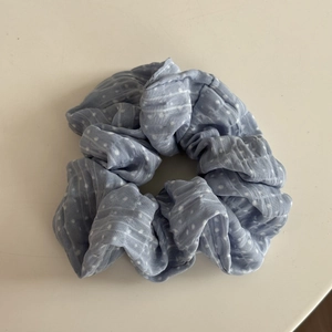 Détail rapproché du chouchou en tissu bleu clair à pois avec texture plissée