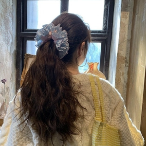 Detail of blue and pink oversized hair scrunchie with lace edges worn by a model