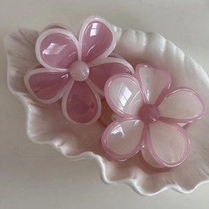 Detailansicht von rosa Blumen-Haarspangen auf einem dekorativen weißen Muscheltablett