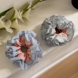 Detail view of blue and pink scrunchies with pleated fabric and fine stitching edges