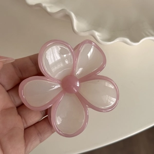 Detailansicht der Haarspange in Blumenform aus glänzendem Harz in Rosa und Creme
