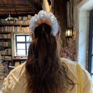 Detail of blue and pink oversized lace scrunchie styled on a ponytail in cozy indoor setting