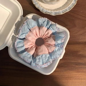 Pink and blue lace scrunchie with layered fabric design in a white paper box