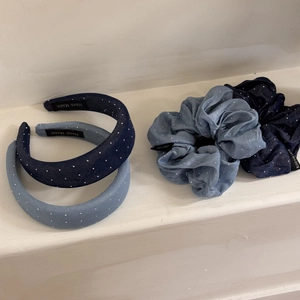 Detailed macro of denim scrunchies and headbands with faux pearls and branded woven labels