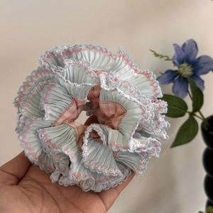 Detail of blue pleated fabric scrunchie with pink wavy crochet edge and checkered inner lining