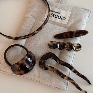Flat lay of tortoiseshell acetate hair accessory set on a grey fabric pouch
