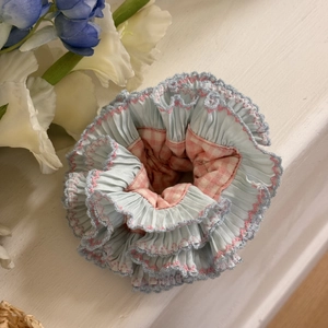 Close-up of double-layered blue scrunchie with pink wavy edges and gingham lining