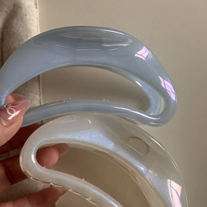 Dettaglio di grandi mollette per capelli azzurro e bianco perla con glitter lucidi