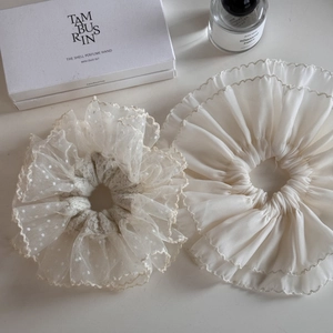 Detailed macro view of white lace and chiffon scrunchies with elegant pleats and textures