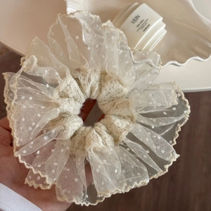 Detail view of white lace scrunchie with delicate embroidery and scalloped edges