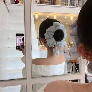 Light blue oversized tulip scrunchie made of chiffon shown in a mirror selfie style