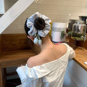 Detail of blue tulip floral scrunchie with ribbons tied in a bun hairstyle