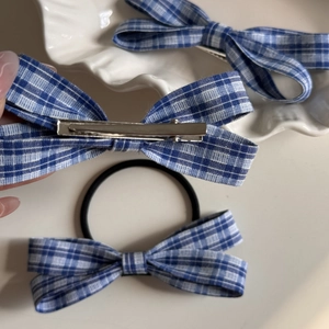 Close-up of blue and white checkered bow hair clips and elastic hair tie on a tray