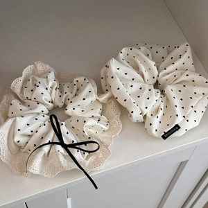 Creamy white heart-patterned scrunchies with lace trim and black bow hair accessory