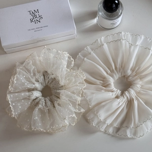 Detail of white lace and pleated chiffon hair scrunchies on elegant vanity background